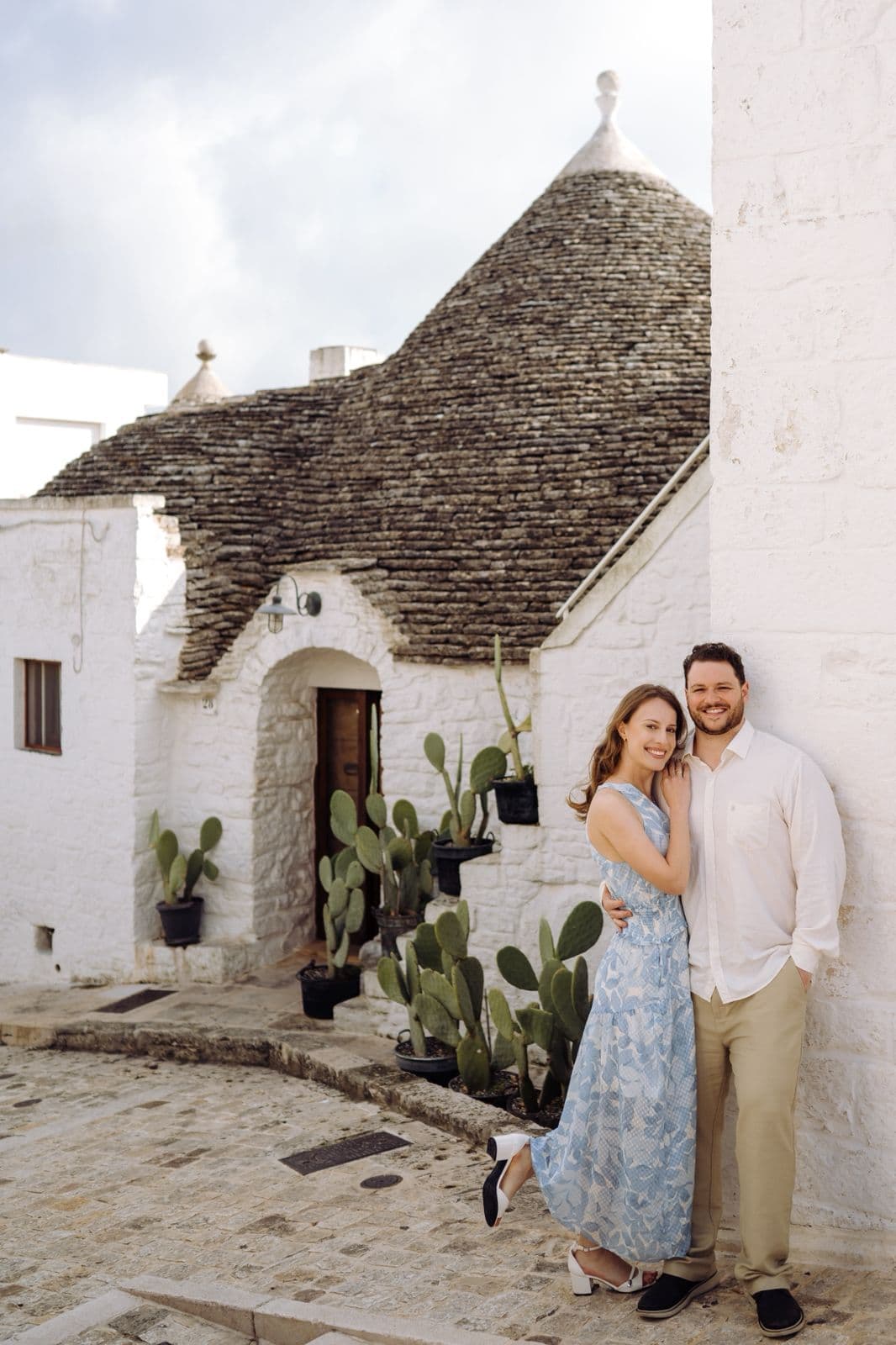 Carol e Alexandre posando em frente aos trulli com cactos de Alberobello